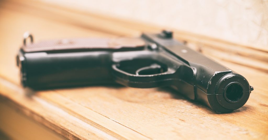 Handgun resting on a wooden table, photographed in soft focus.