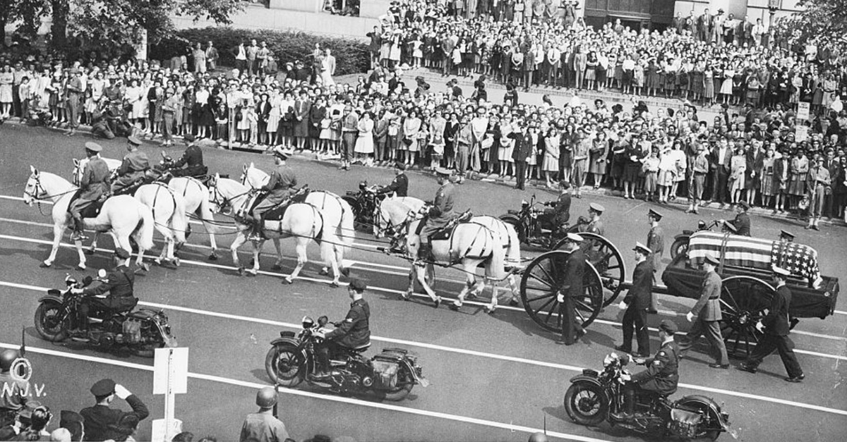 FDR’s flag-draped casket on a horse-drawn caisson during the funeral procession in Washington, D.C., as crowds line the street.