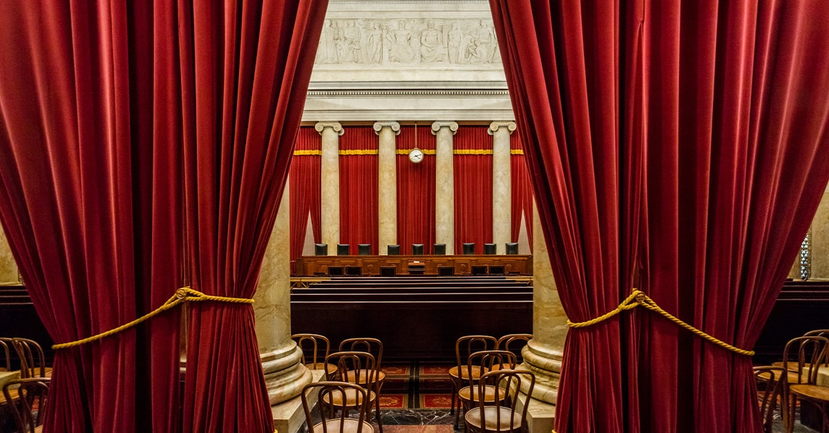 Interior view of the U.S. Supreme Court chamber with red curtains, empty chairs, and the judge’s bench, symbolizing the Court’s ruling that age verification laws for online porn access are constitutional to protect children.