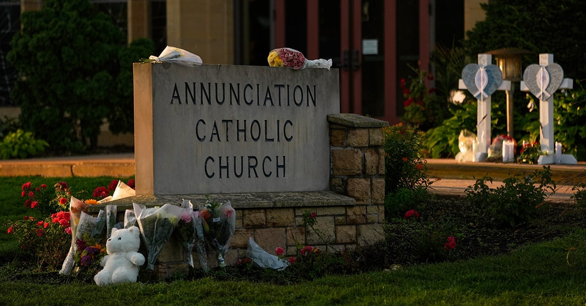 Flowers and teddy bears left by mourners at the entrance sign of Annunciation Catholic Church in Minneapolis