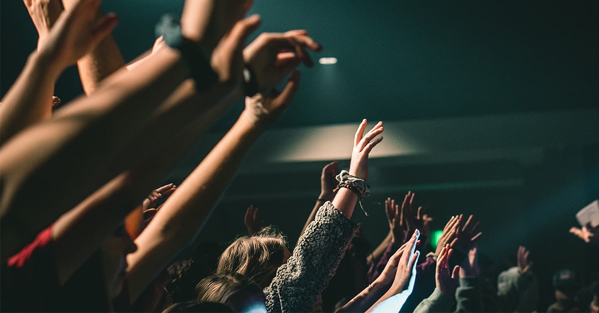 Young people raising their hands in worship and prayer at a Christian church service
