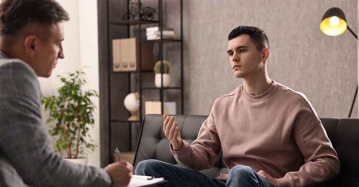 A male counselor talks to a distressed young patient.