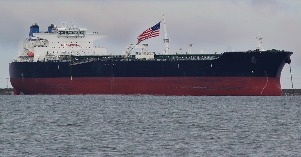A U.S. ship carrying crude oil and flying a U.S. flag floats on the water near the shore of Washington State.