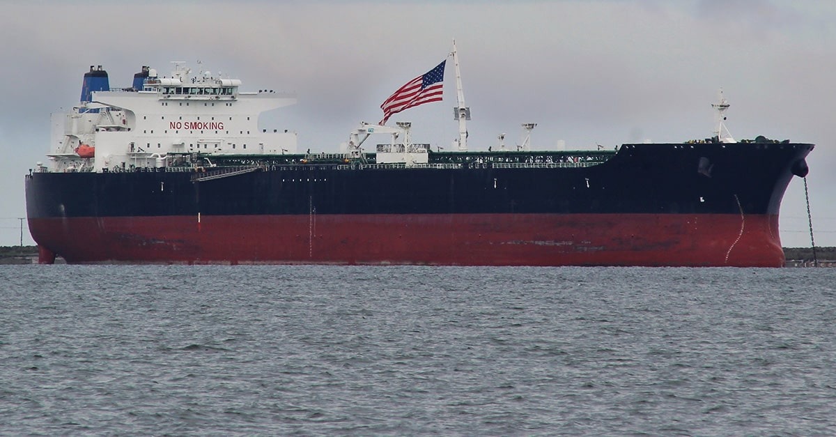 A U.S. ship carrying crude oil and flying a U.S. flag floats on the water near the shore of Washington State.