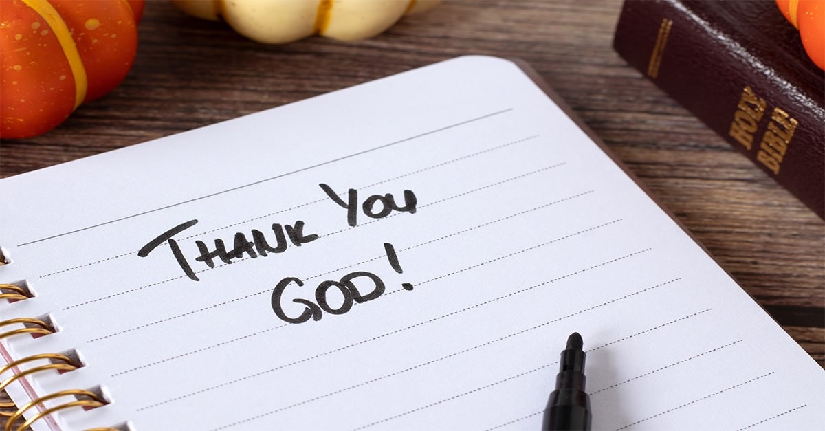 A notepad with the words "Thank You God!" surrounded by a Thanksgiving dinner setting.