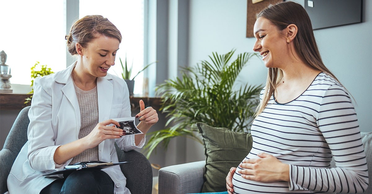 A medical professional shows a pregnant woman an ultrasound photo of her baby.