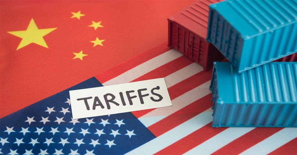The flags of China and the United States serve as background to a photo of shipping containers and the word "Tariffs"