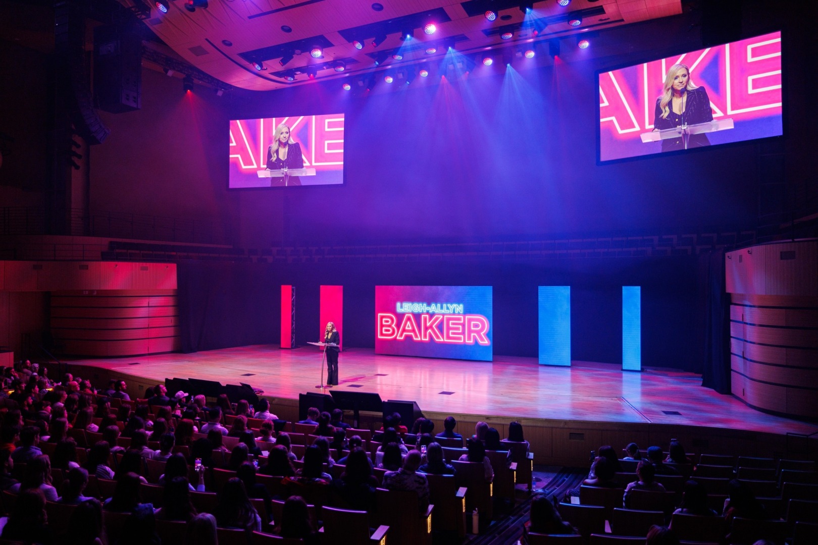 Wide shot of Leigh-Allyn Baker speaking at the 2025 Freedom Uncensored event with some of the crowd in frame