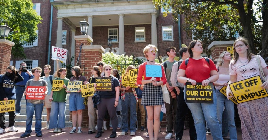 Students stand on the sidewalk out their school holding signs like "ICE Out" and "Free DC."