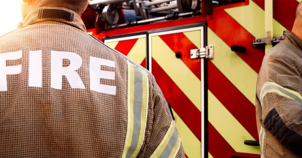 Firefighters stand beside a fire truck, illustrating the Austin Fire Department case involving former chaplain Andrew Fox.