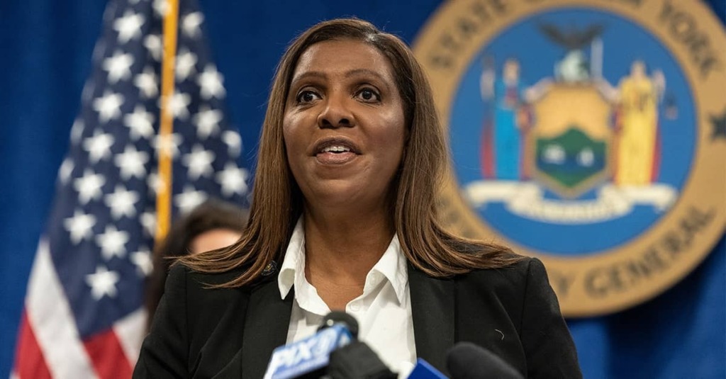 New York Attorney General Letitia James speaks at a podium with microphones in front of a New York state seal and an American flag.