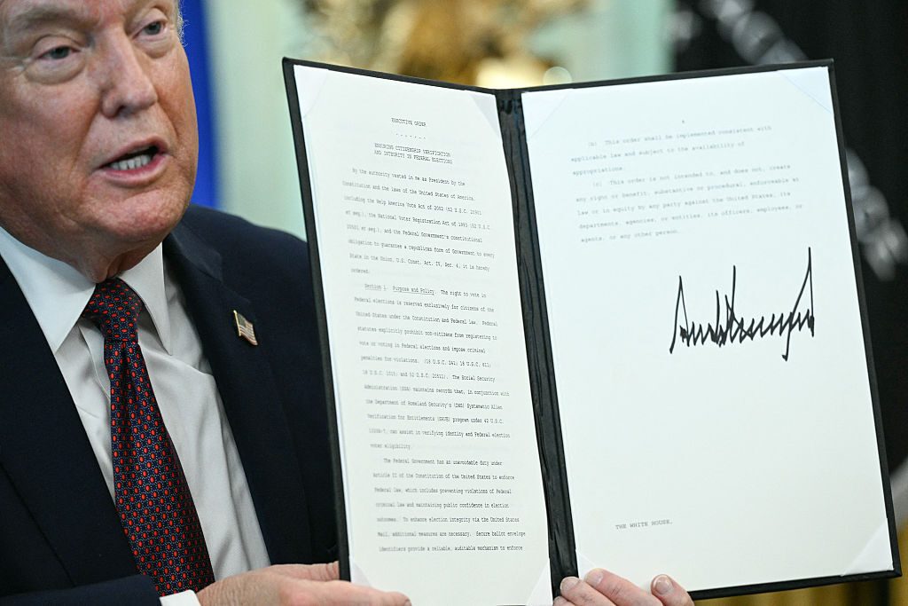 President Donald Trump displays a signed election-integrity executive order in the Oval Office.