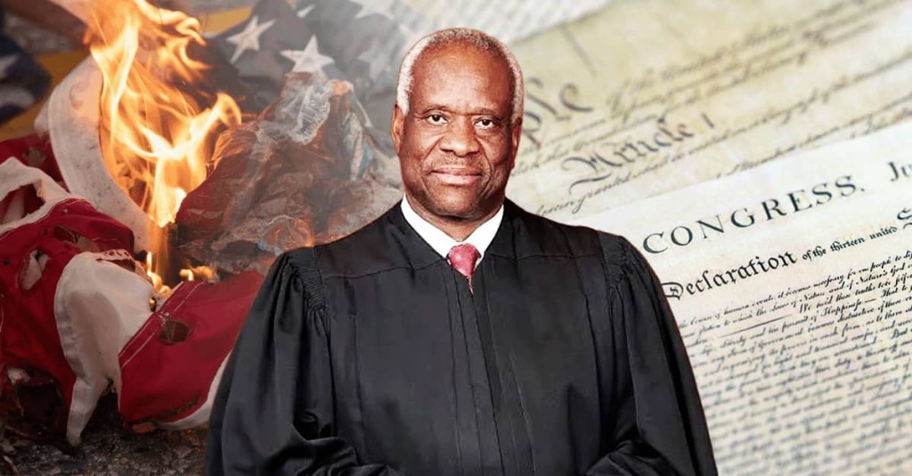 Justice Clarence Thomas in judicial robes stands before imagery of the U.S. Constitution and a burning American flag, symbolizing his warning about threats to America’s constitutional order.