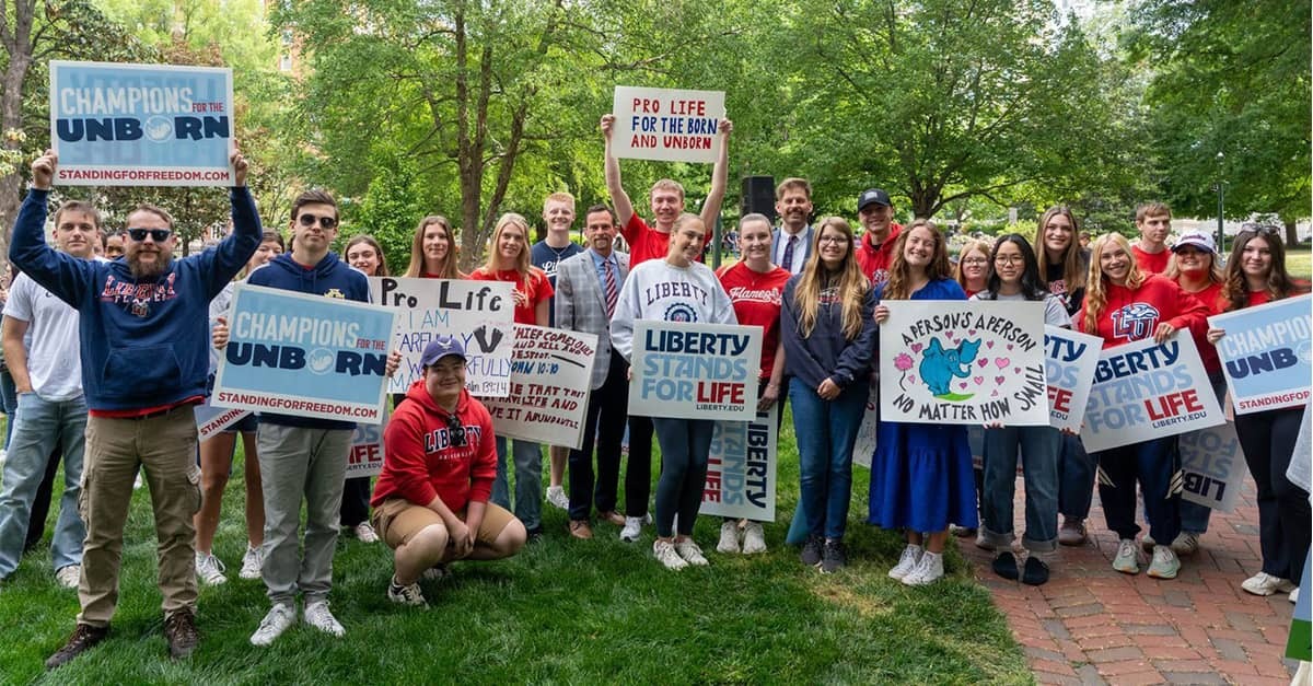 Liberty University students and pro-life advocates gather outdoors in Richmond at the 2026 Virginia March for Life, holding signs that read “Liberty Stands for Life,” “Champions for the Unborn,” and “Pro Life for the Born and Unborn.”