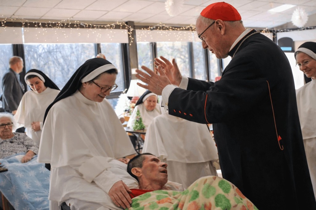 A priest and nun pray over a dying patient lying in a bed at Rosary Hill Home in New York.
