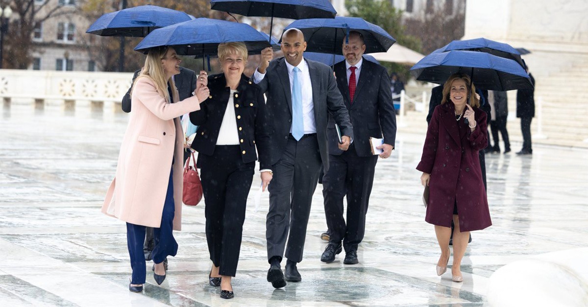 Aimee Huber (second from left), executive director of Women's Choice Health Resource Center, walking under umbrellas outside the U.S. Supreme Court, celebrating with her legal team after learning of the Supreme Court's unanimous ruling in her favor.
