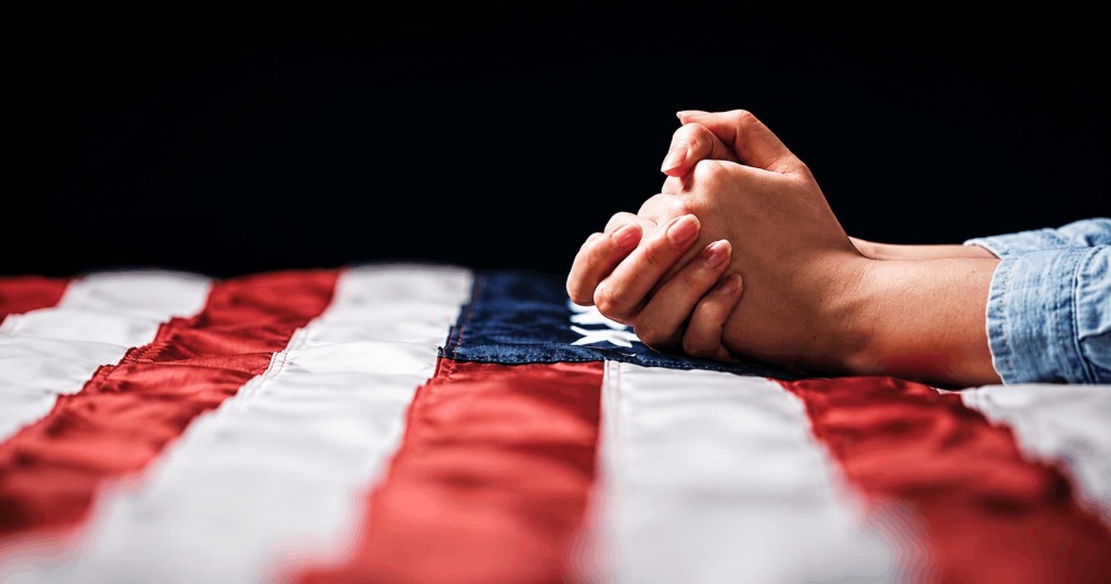 Praying hands on an American flag
