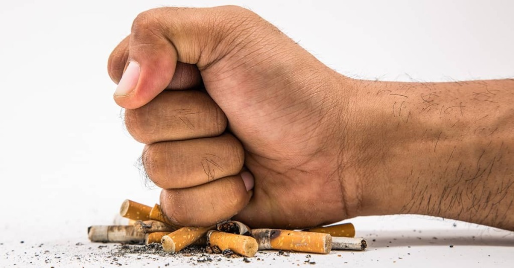 A clenched fist crushes cigarette butts, symbolizing Britain’s birth-year tobacco sales ban for anyone born after 2008.