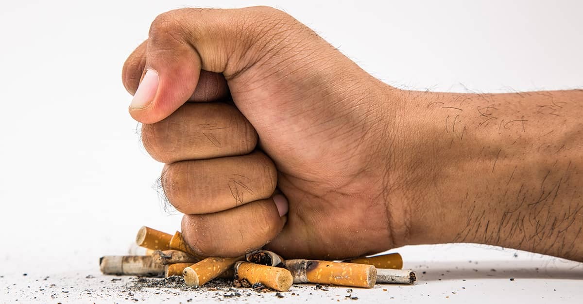 A clenched fist crushes cigarette butts, symbolizing Britain’s birth-year tobacco sales ban for anyone born after 2008.