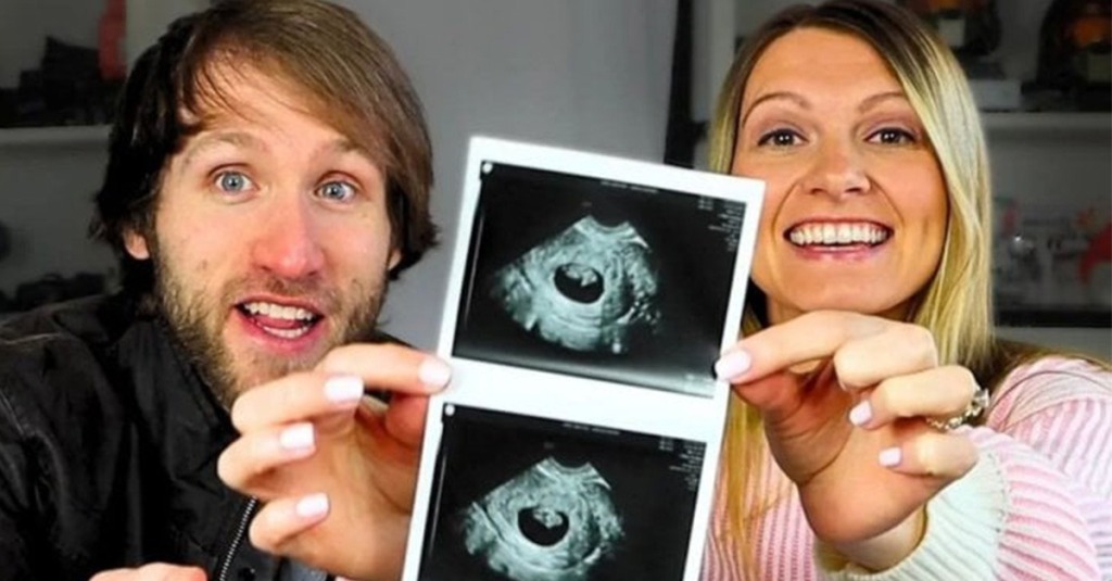 Jesse and Ashley Ridgway smile happily as they hold up an ultrasound photo of their unborn child.