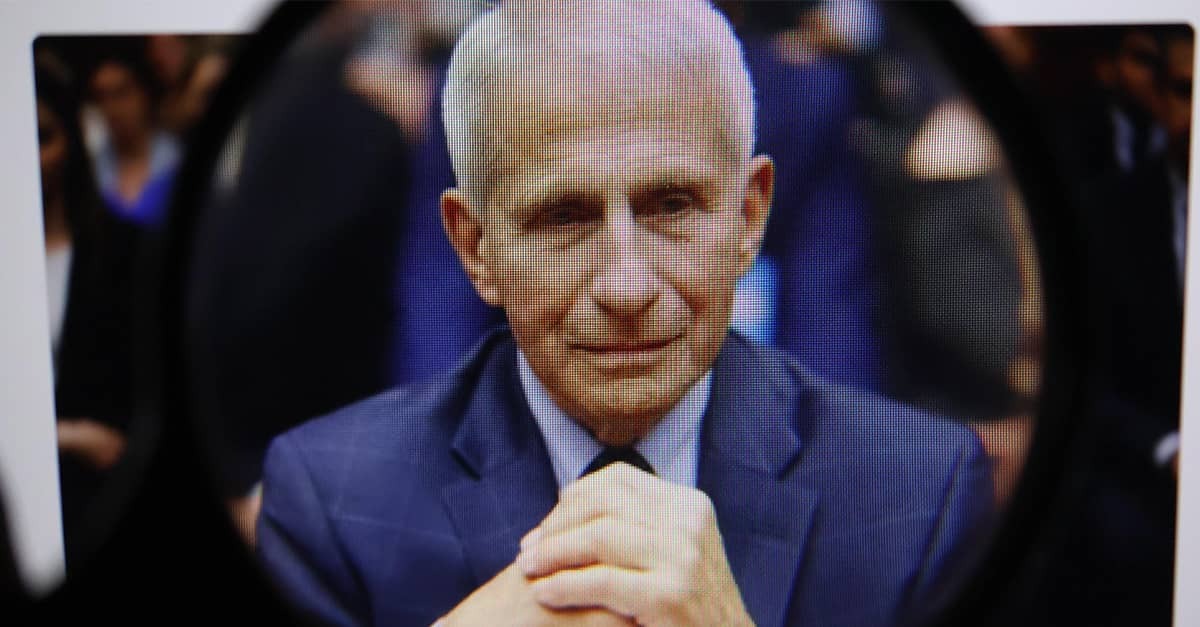 Dr. Anthony Fauci sits with hands folded at a table in front of a congressional subcommittee.