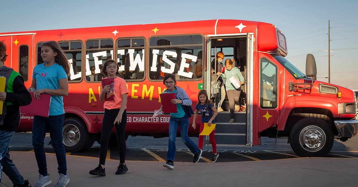 Several children carrying Bibles and notebooks are seen getting off a LifeWise Academy bus.