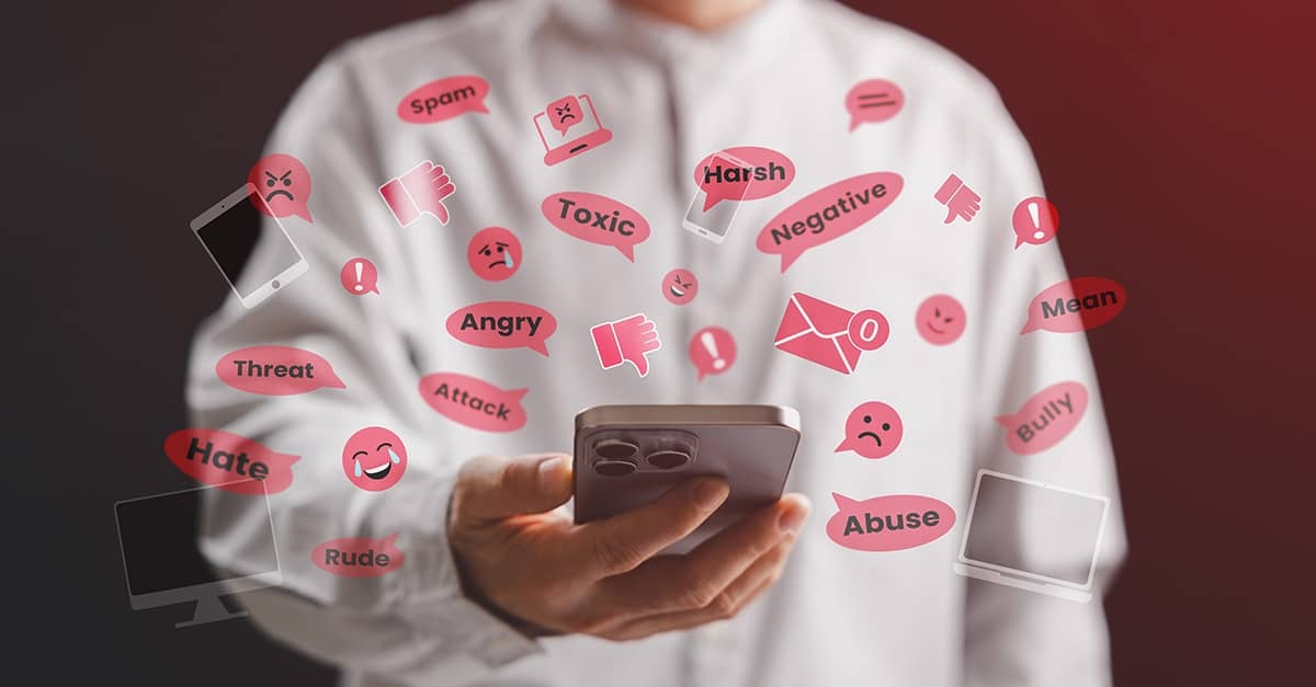 a man holding a smartphone surrounded by vile words and emojis.